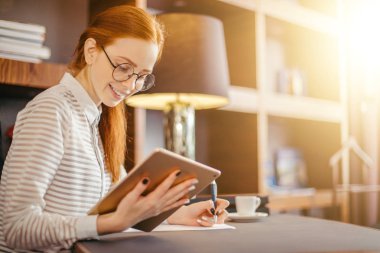 Kızıl saçlı gülümseyen genç kadın Yöneticisi ofiste modern dijital tablet kullanma