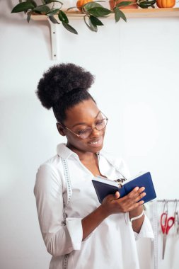 Afrikalı terzi kız not defterine not alıyor. Tasarımcı çizimleri