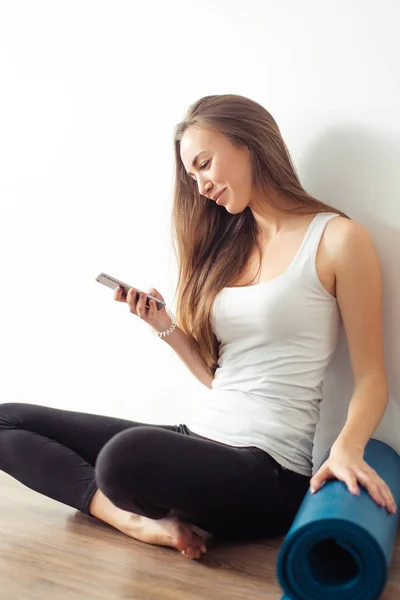 woman doing yoga and using cell phone sitting on the floor
