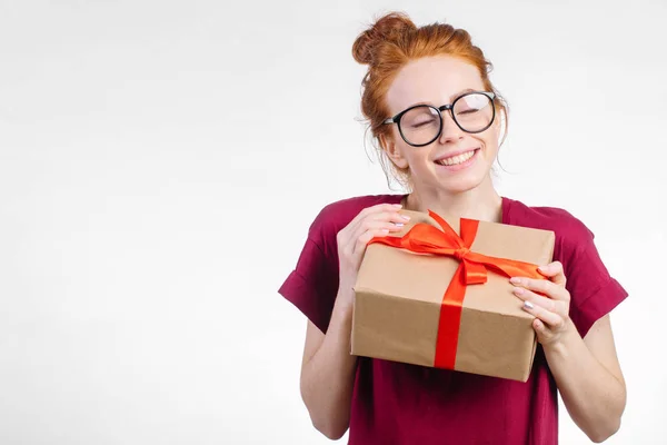 Mujer pelirroja feliz en gafas sosteniendo caja de regalo sobre fondo blanco —  Fotos de Stock