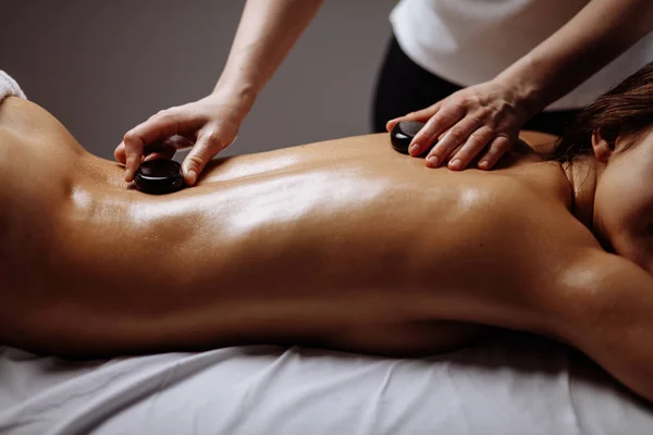 Jonge vrouw getting hot stone-massage op spa salon — Stockfoto
