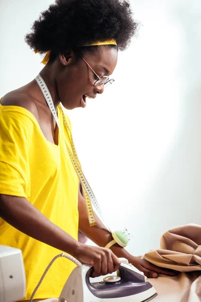 Africký žena švadlena žehlící látka — Stock fotografie