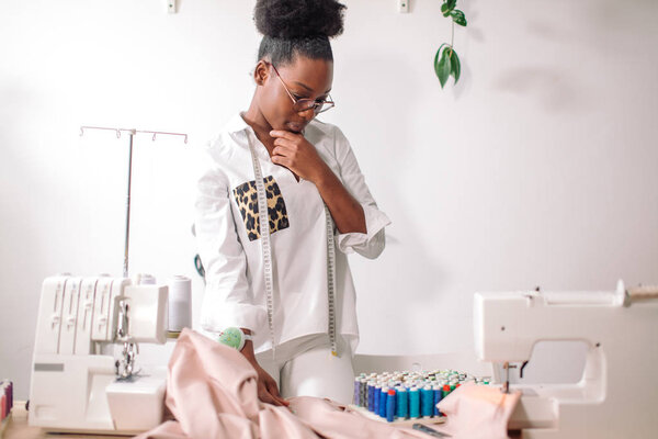 young woman seamstress thinking and working in studio