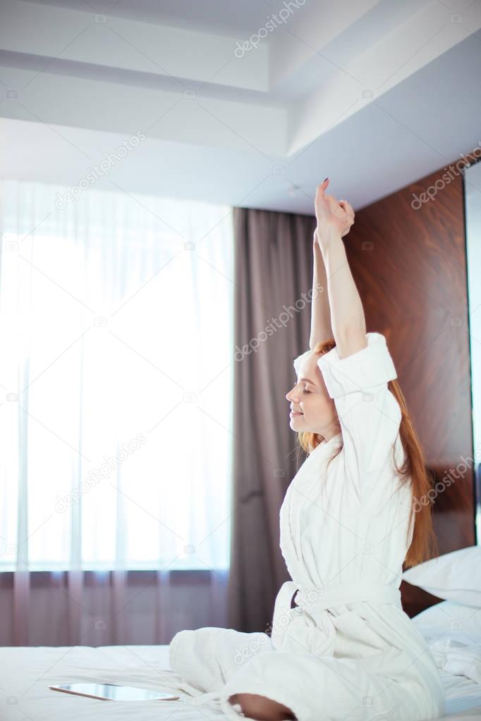 Redhead Woman stretching in bed after waking up