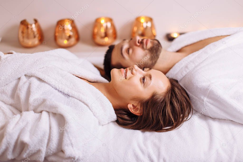 man and woman lying down on massage beds at luxury spa and wellness center