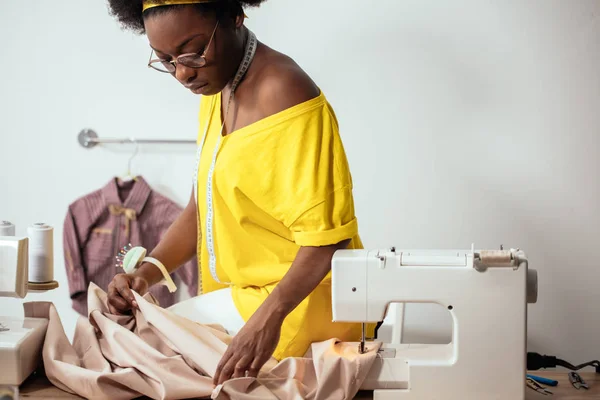 Costurera mujer africana mirando telas rosadas y de pie en el taller — Foto de Stock