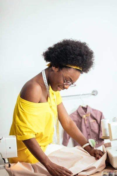 Costurera mujer africana mirando telas rosadas y de pie en el taller — Foto de Stock