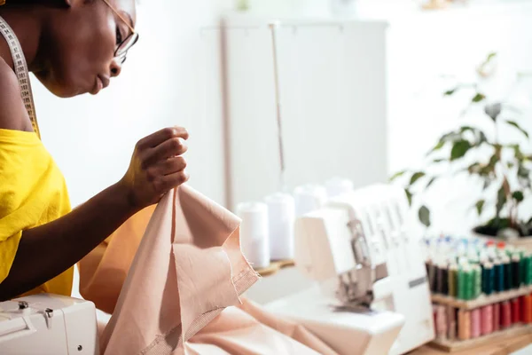 Costurera mujer africana mirando telas rosadas y de pie en el taller —  Fotos de Stock