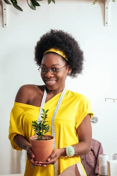 Africano ragazza sorridente guardando fotocamera tenendo fiore pot in mano — Foto Stock