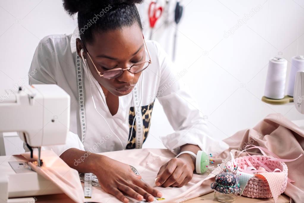 african seamstress working with fabric takes measures