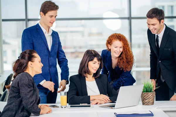 Мужчины и женщины деловые люди вокруг ноутбука в офисе — стоковое фото