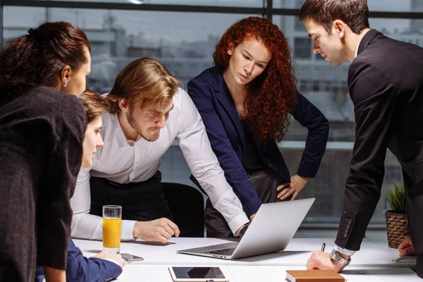 Hombres y mujeres de negocios alrededor de computadoras portátiles en la oficina — Foto de Stock