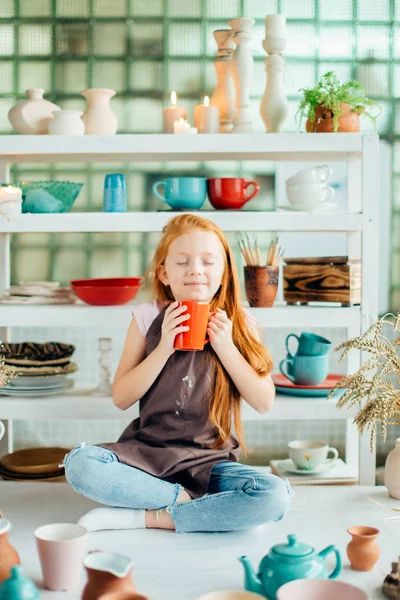 Flicka wih många koppar gjorda av lera som sitter i keramikateljé — Stockfoto