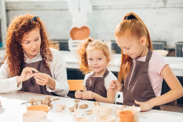 Redhead mother and two daughter mold with clay, pottery children — Stock Photo, Image