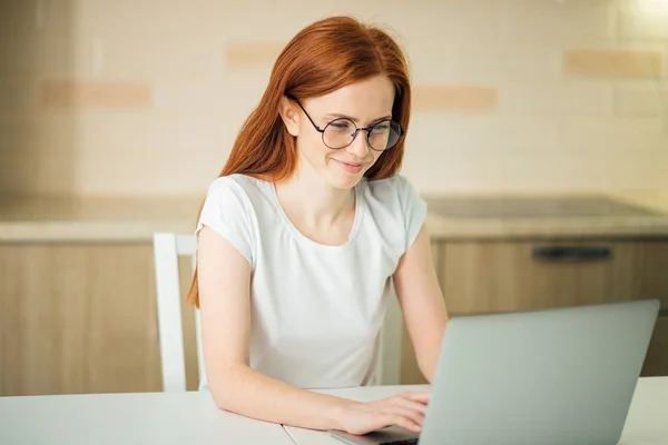 Красивая молодая женщина улыбается и смотрит на экран ноутбука — стоковое фото