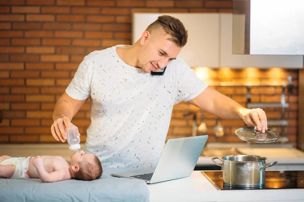 Pai alimentando seu bebê ao tentar trabalhar no laptop — Fotografia de Stock