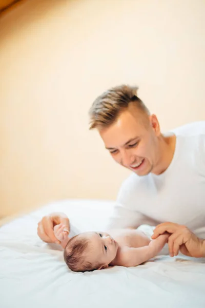 Padre acostado en la cama y sostiene a su bebé —  Fotos de Stock