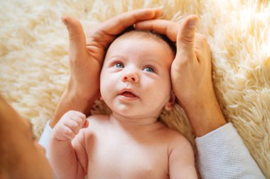Kameraya bakıyor bebeğim, beyaz battaniye üzerinde yatıyordu