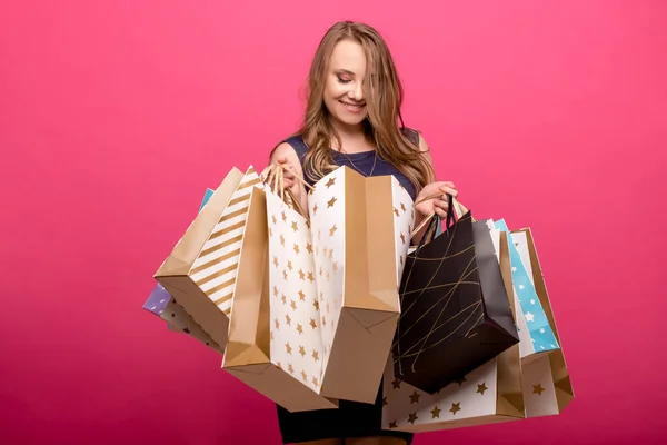Onun elleri büyük alışveriş çantası pembe bir arka plan üzerinde tutan sürpriz kadın kız — Stok fotoğraf