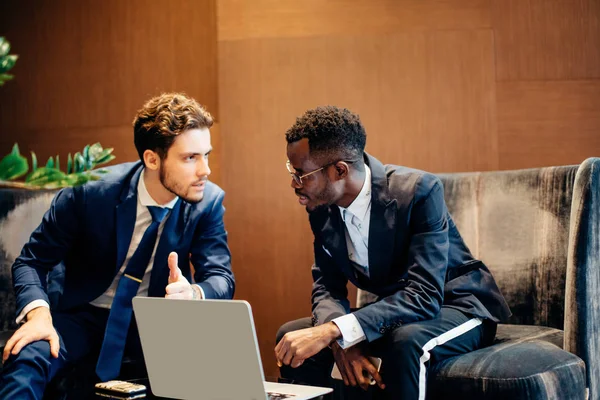 Homem de negócios usando laptop para discutir informações com colega no escritório moderno — Fotografia de Stock
