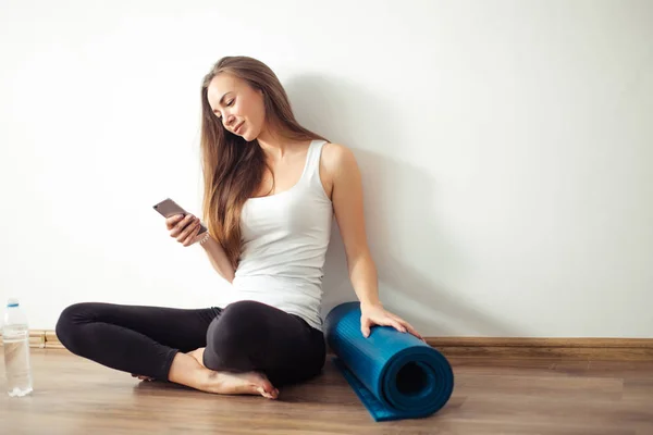 Mujer haciendo yoga y usando el teléfono celular sentado en el suelo — Foto de Stock