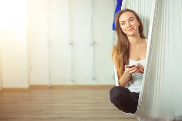 woman posing in anti-gravity aerial yoga hammock. relax with phone