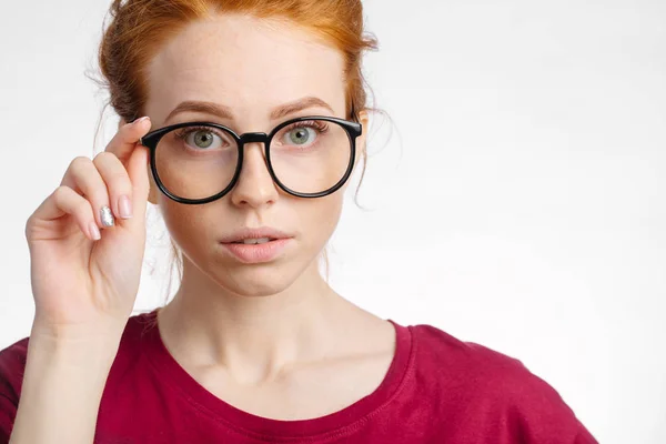 Redhead smiling woman wearing red shirt hold glasses on white background — Stock Photo, Image