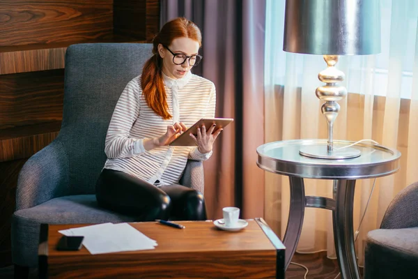 Junge Frau mit langen Haaren mit Tablet und lächelnd auf Sofa sitzend — Stockfoto