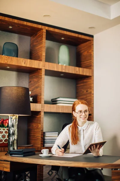 Rothaarige lächelnde junge Managerin nutzt modernes digitales Tablet im Büro — Stockfoto