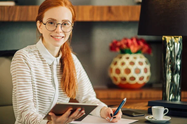 Hermosa mujer joven sosteniendo la tableta digital y mirando a la cámara con sonrisa — Foto de Stock