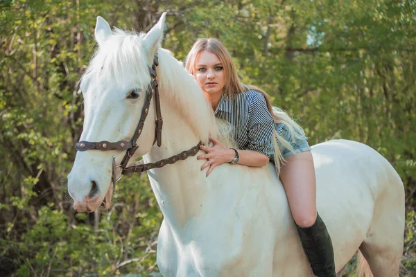 Brunette woman riding dark horse at summer green forest. — Stock Photo, Image