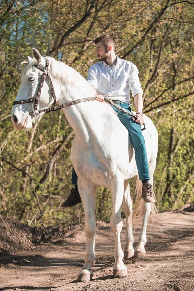 Hombre con camisa montada en un caballo marrón — Foto de Stock