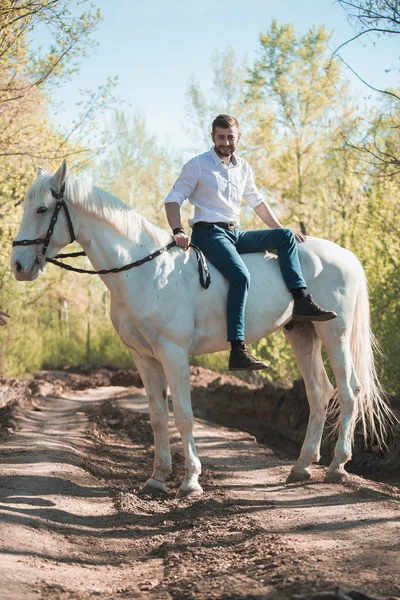 Hombre con camisa montada en un caballo marrón — Foto de Stock