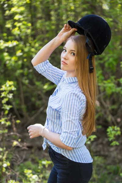 girl in riding clothes and helmet on a light background, the concept of jockey