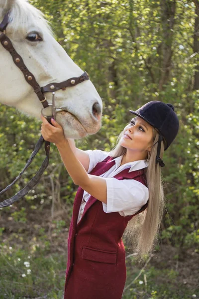 Schöne brünette Mädchen mit langen Haaren posiert mit einem roten Pferd im Wald — Stockfoto