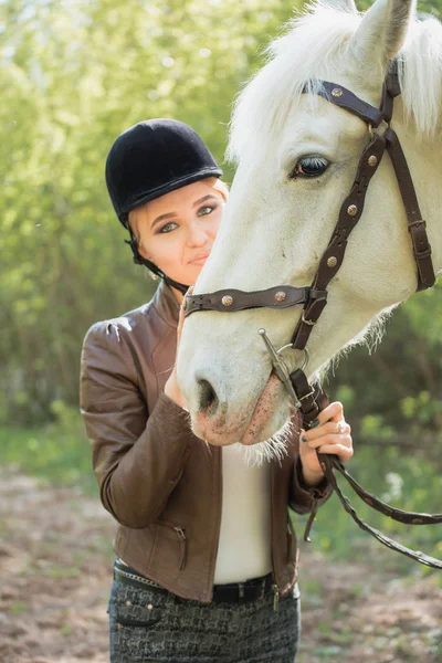 Krásná brunetka s dlouhými vlasy pózuje s červeným koněm v lese — Stock fotografie