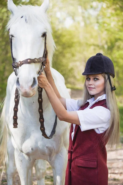 Beautiful brunette girl with long hair posing with a red horse in forest — Stock Photo, Image