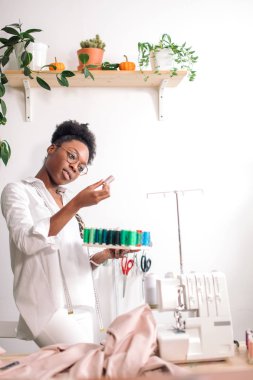 Afrikalı terzi kadın ipliklerle bobinler tutuyor.