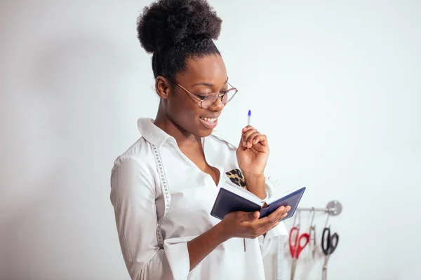 Africká dívka švadlena dělat poznámky do zápisníku. kresby návrháře — Stock fotografie