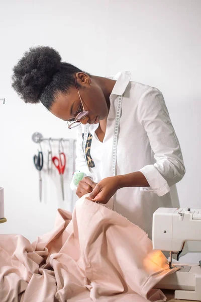 Afrikaanse vrouw naaister kijken naar roze stoffen en staan in workshop — Stockfoto