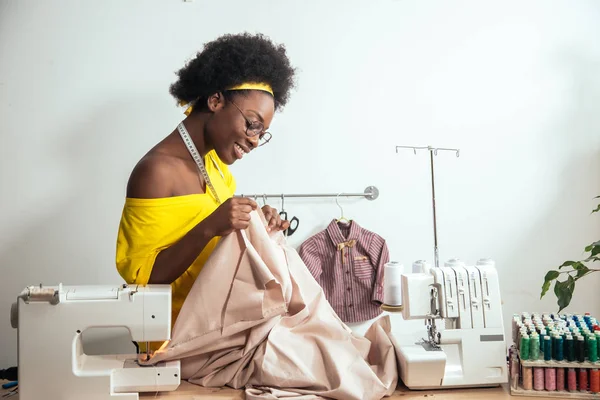 Afrikanische Näherin betrachtet rosa Stoffe und steht in der Werkstatt — Stockfoto