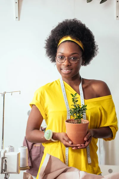 Africano ragazza sorridente guardando fotocamera tenendo fiore pot in mano — Foto Stock