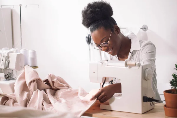 Costurera mujer sentado y cose en la máquina de coser. Dressmaker trabajando — Foto de Stock