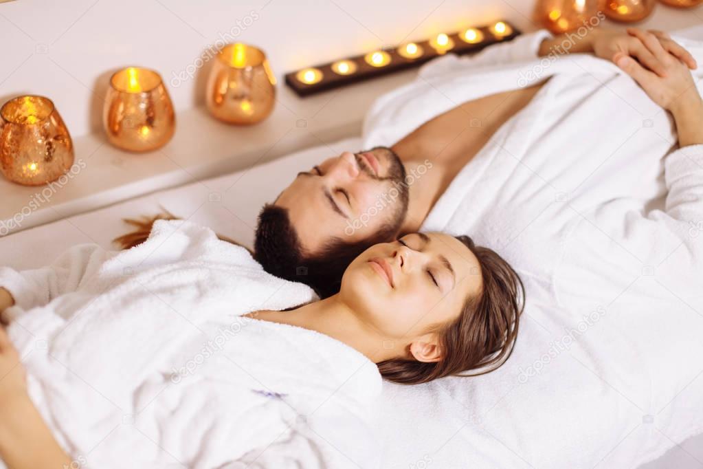 man and woman lying down on massage beds at luxury spa and wellness center