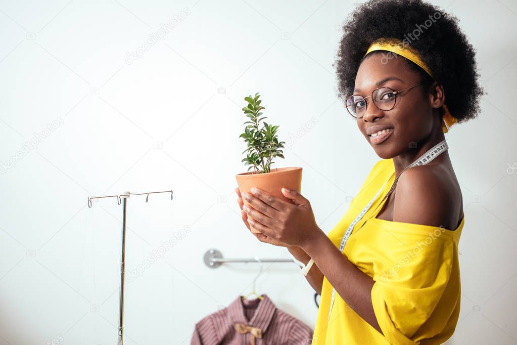 african girl smiling looking at camera holding flower pot in hands
