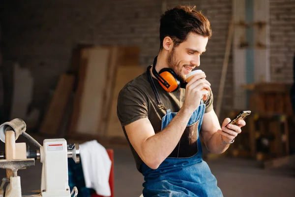 Homem usando telefone inteligente e segurando xícara de café — Fotografia de Stock