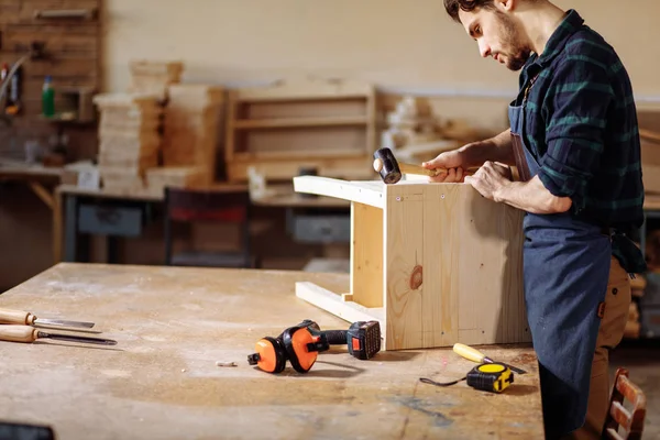 Timmerman een nagel hameren in houten plank — Stockfoto