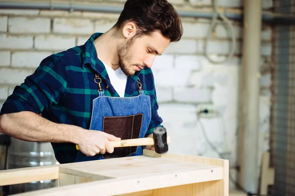 Timmerman een nagel hameren in houten plank — Stockfoto