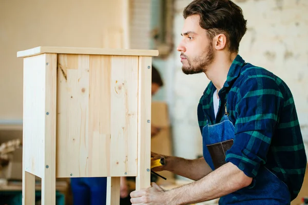 Timmerman testen houten plank gelijkmatigheid op workshop — Stockfoto