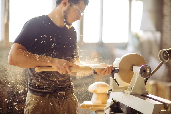 O homem que trabalha no torno de madeira pequeno, um pedaço de madeira do carves do artesão — Fotografia de Stock